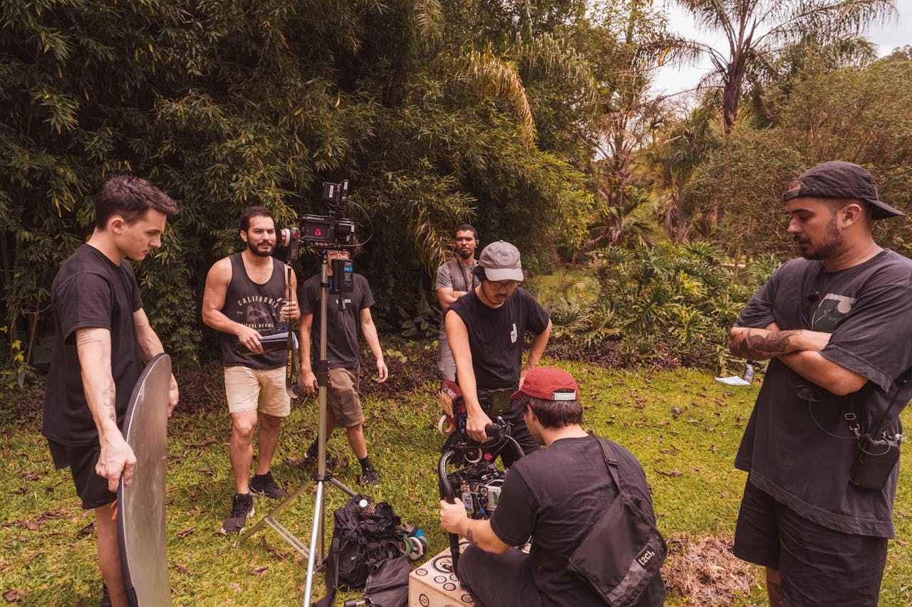 Group of men setting up camera equipment for a film shoot in a lush forest.